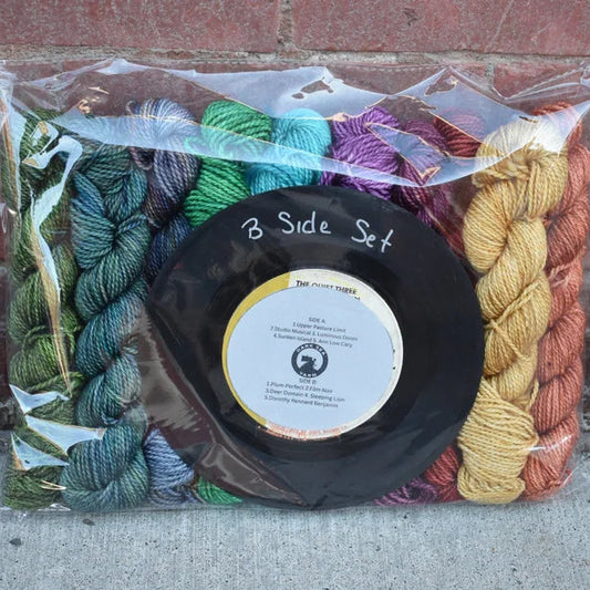 Packaged yarn set with a vinyl record on a concrete surface.