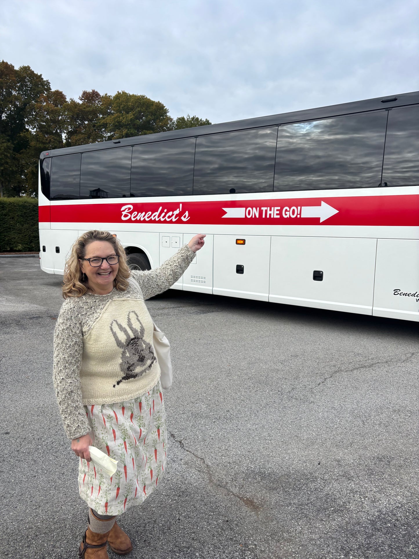 Woman pointing at a large bus with 'Benedict's On the Go!' branding.