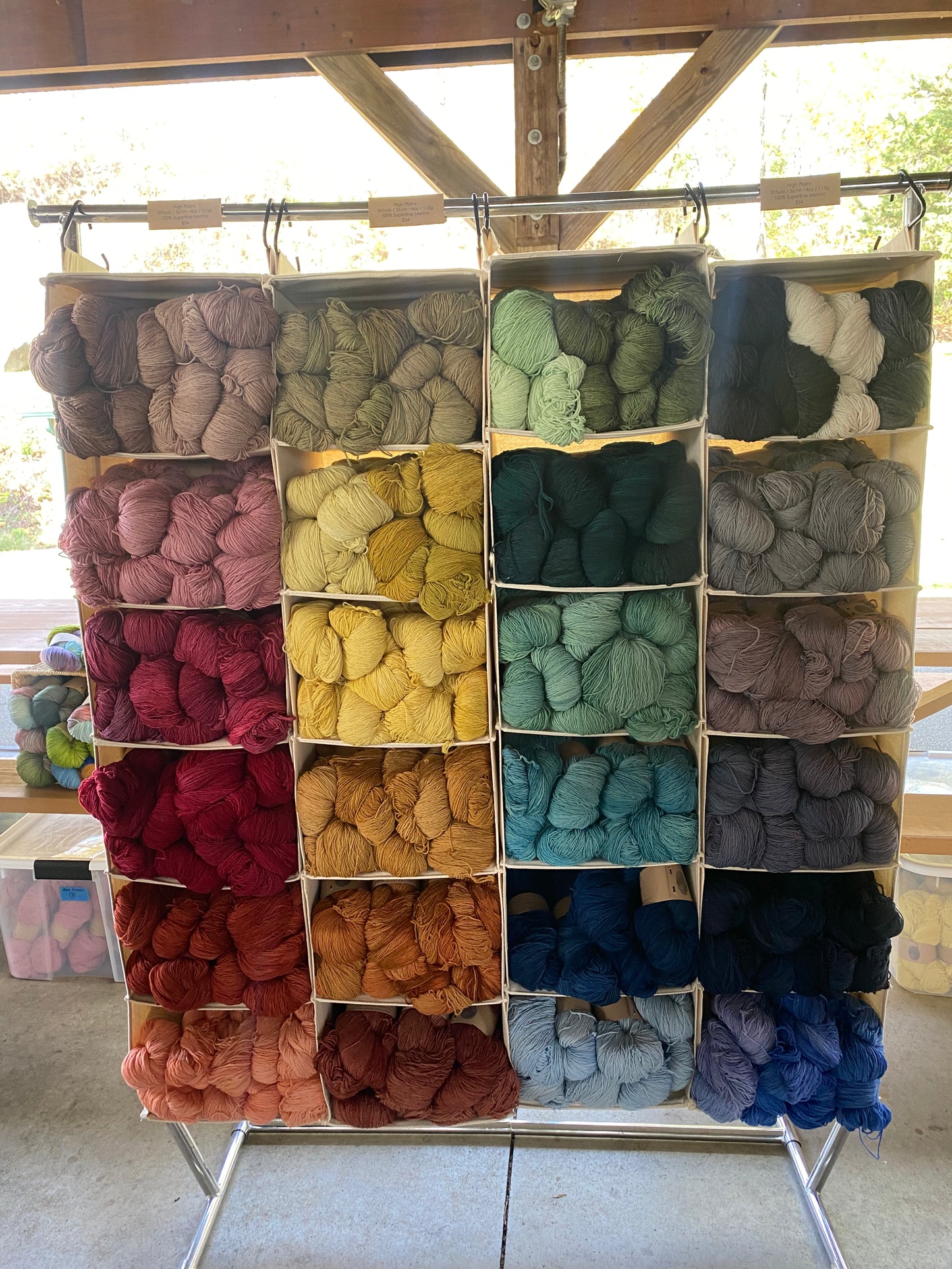 Yarn display with various colors on a metal rack outdoors.